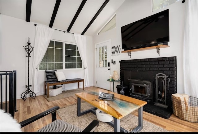 living room with hardwood / wood-style flooring, vaulted ceiling with beams, and a fireplace