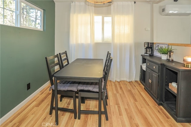 dining space with light hardwood / wood-style flooring and a wall mounted air conditioner