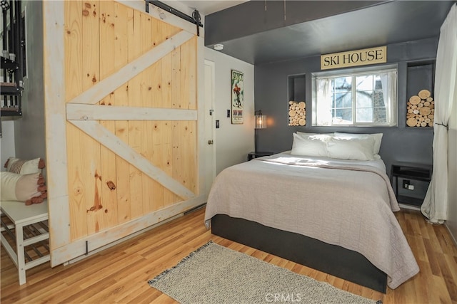 bedroom with an AC wall unit, hardwood / wood-style floors, and a barn door