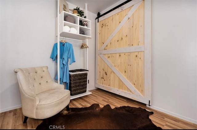 living area with a barn door and wood-type flooring