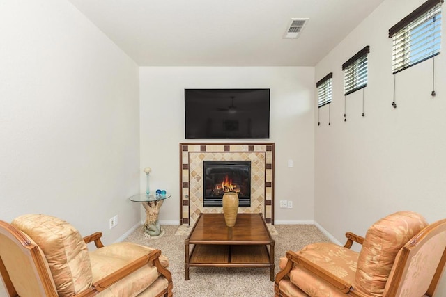 living area with a tiled fireplace and light carpet