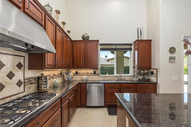 kitchen featuring appliances with stainless steel finishes, a wealth of natural light, dark stone countertops, and sink