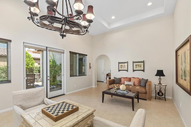 living room with a raised ceiling, a towering ceiling, and an inviting chandelier