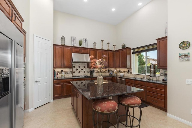 kitchen with sink, tasteful backsplash, dark stone countertops, a kitchen island, and appliances with stainless steel finishes