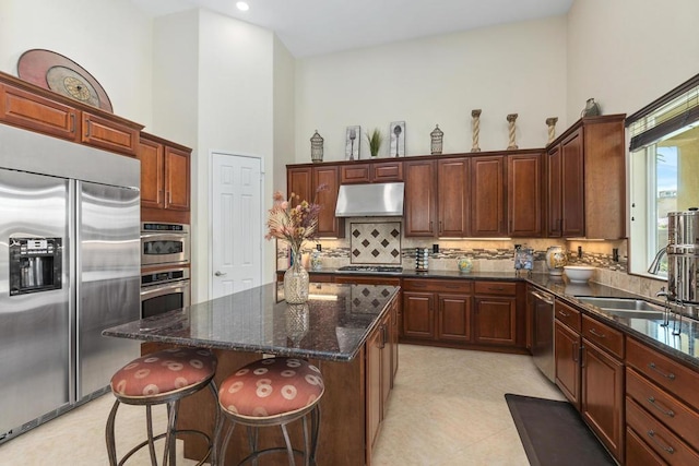 kitchen with high vaulted ceiling, sink, dark stone countertops, tasteful backsplash, and stainless steel appliances