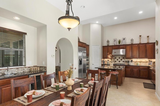 dining room featuring sink, light tile patterned flooring, and a high ceiling