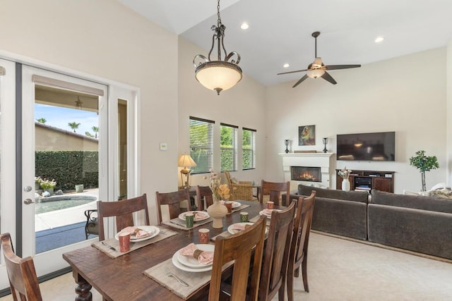 carpeted dining area featuring ceiling fan and a towering ceiling