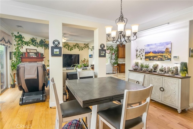 dining space with crown molding, ceiling fan with notable chandelier, and light wood-type flooring