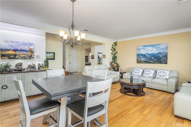 dining space featuring light hardwood / wood-style floors, ornamental molding, and an inviting chandelier