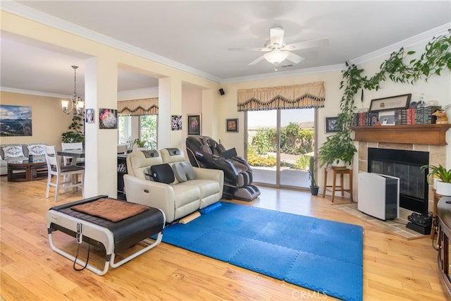 living room featuring light hardwood / wood-style flooring, crown molding, and a tiled fireplace