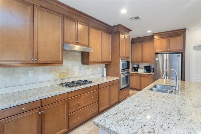 kitchen featuring decorative backsplash, stainless steel appliances, light stone counters, and sink