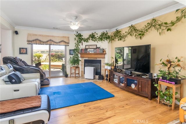 living room with ceiling fan, light hardwood / wood-style floors, ornamental molding, and a fireplace