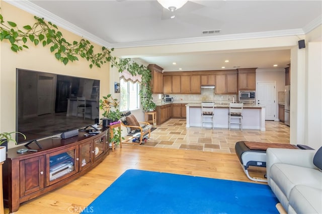 living room with ceiling fan, light hardwood / wood-style floors, and ornamental molding