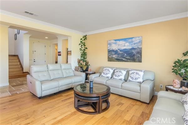 living room with light wood-type flooring and crown molding