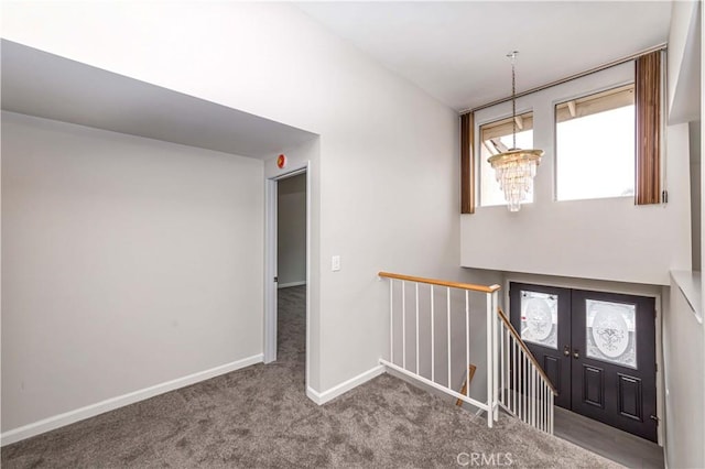 carpeted foyer featuring a chandelier and french doors