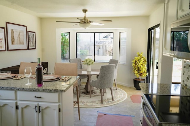 kitchen featuring ceiling fan, white cabinetry, stainless steel appliances, light stone counters, and light tile patterned flooring