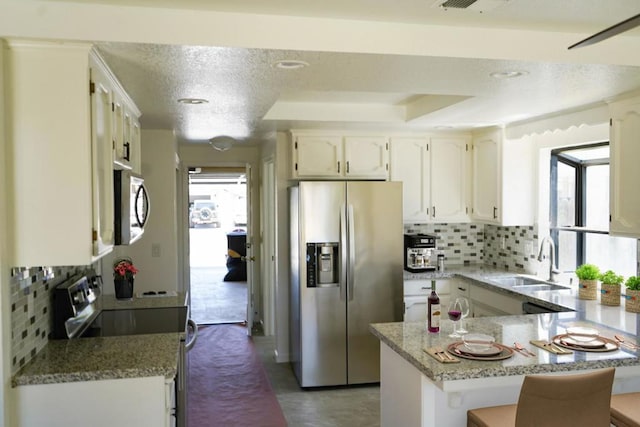 kitchen with sink, tasteful backsplash, white cabinetry, kitchen peninsula, and stainless steel appliances