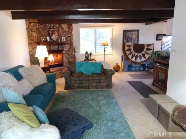 living room with carpet floors, beamed ceiling, and a stone fireplace