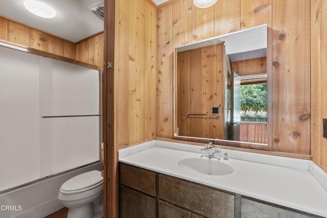 full bathroom with toilet, vanity, shower / bath combination with glass door, and wood walls