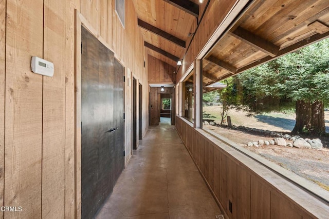 hallway featuring wooden ceiling, lofted ceiling with beams, and wood walls