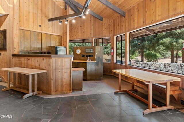 kitchen featuring beam ceiling, track lighting, and wooden walls