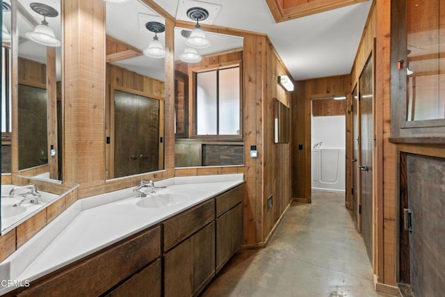 bathroom with concrete flooring, vanity, and wood walls