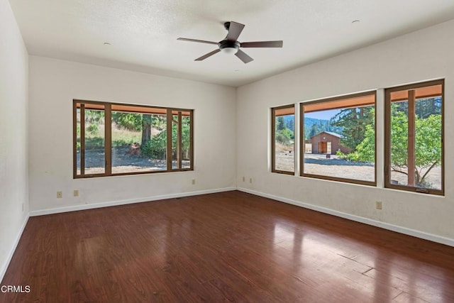 spare room with dark wood-type flooring, a wealth of natural light, and ceiling fan