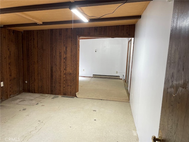 basement with carpet, a baseboard heating unit, and wooden walls