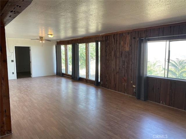 spare room featuring hardwood / wood-style floors, a healthy amount of sunlight, and wood walls