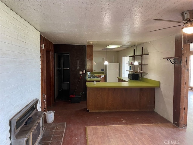 kitchen featuring dark hardwood / wood-style floors, hanging light fixtures, kitchen peninsula, white refrigerator, and a textured ceiling