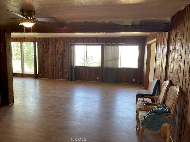 unfurnished room with a healthy amount of sunlight, wooden walls, and ceiling fan