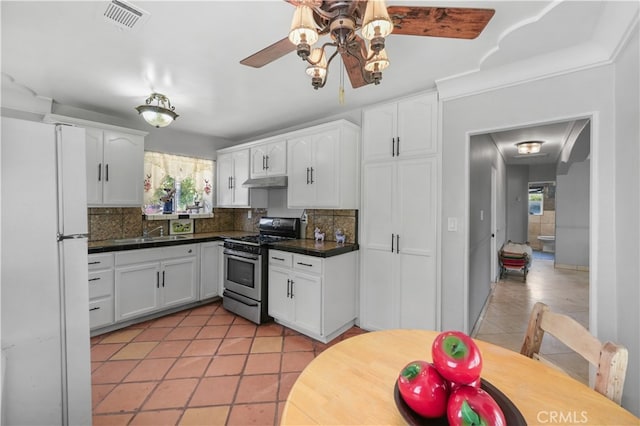 kitchen with white cabinets, gas stove, white refrigerator, and tasteful backsplash