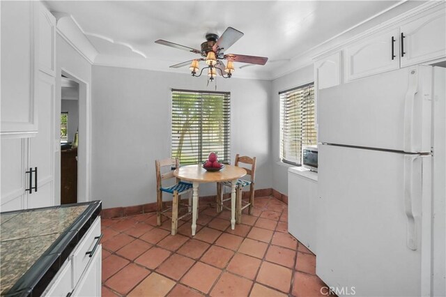 kitchen featuring white fridge, white cabinetry, ceiling fan, and crown molding