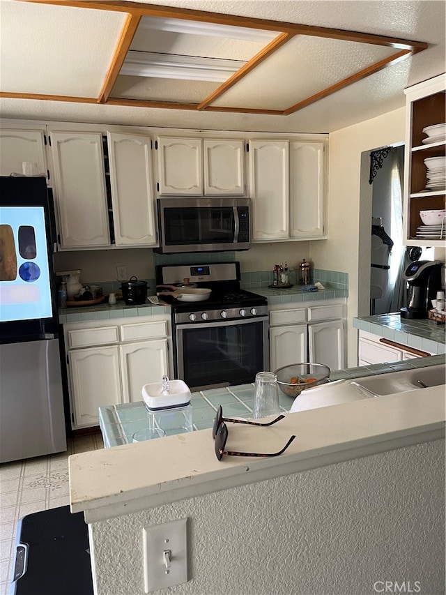 kitchen featuring stainless steel appliances, a textured ceiling, and white cabinetry