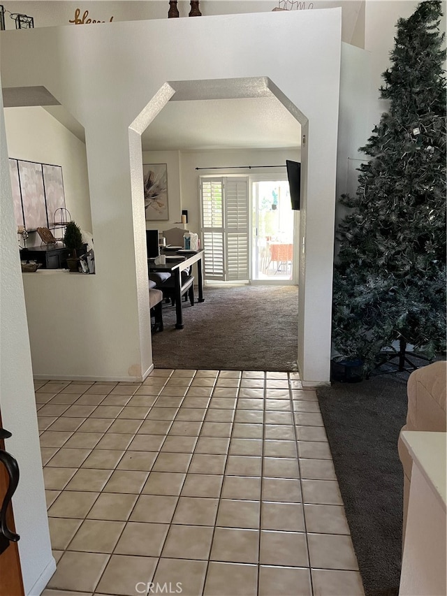 corridor with light colored carpet and a textured ceiling