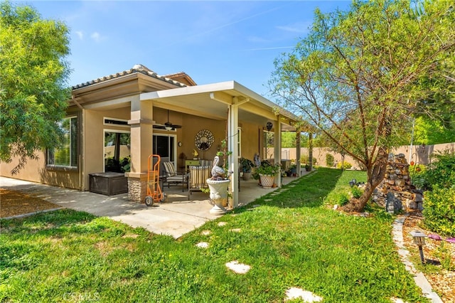 back of property featuring a lawn, ceiling fan, and a patio