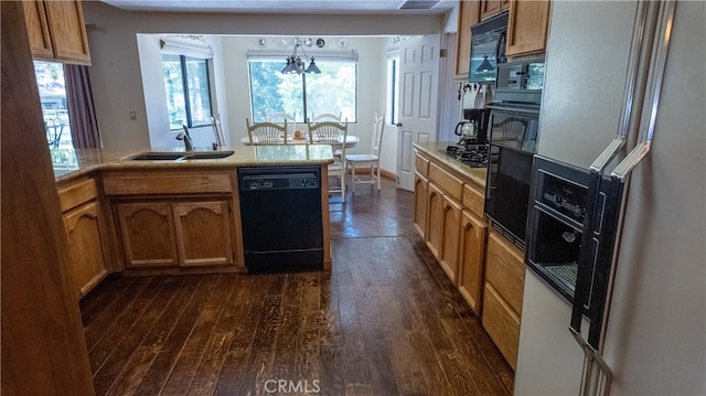 kitchen with dark wood-type flooring, sink, black appliances, and a notable chandelier