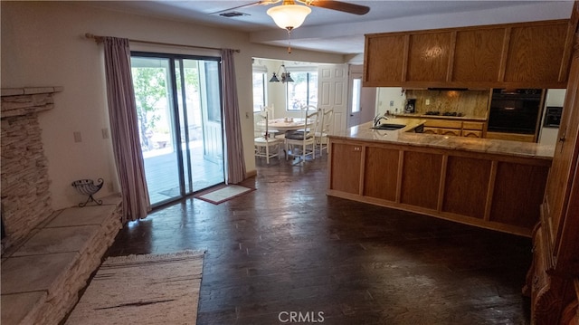 kitchen featuring kitchen peninsula, gas stovetop, ceiling fan, sink, and black oven