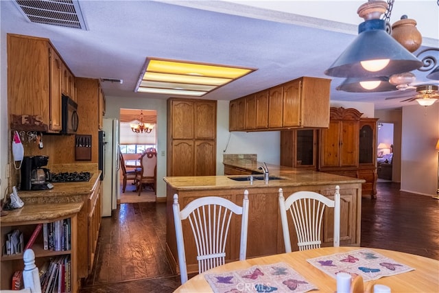 kitchen featuring kitchen peninsula, dark hardwood / wood-style flooring, ceiling fan with notable chandelier, sink, and black appliances