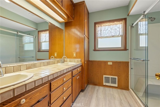 full bath with a shower with door, visible vents, a sink, a wainscoted wall, and wood finished floors