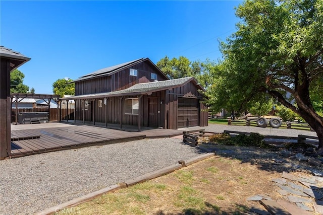 rear view of house with a deck, a garage, and a jacuzzi
