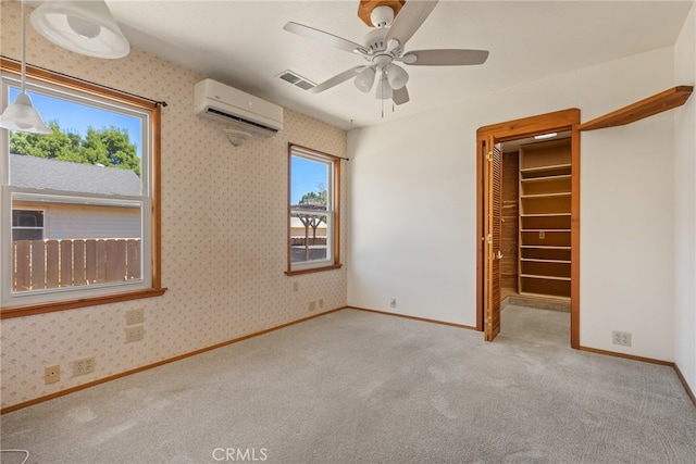 unfurnished bedroom featuring a spacious closet, a closet, a wall unit AC, and light colored carpet