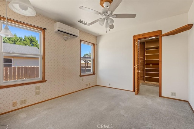 unfurnished bedroom with carpet flooring, a wall unit AC, wallpapered walls, visible vents, and baseboards