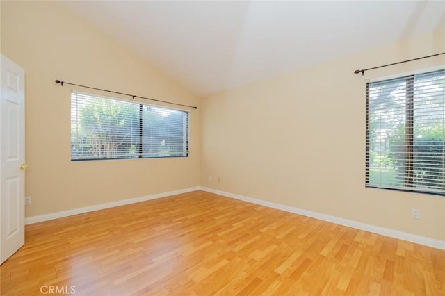 spare room with hardwood / wood-style flooring and vaulted ceiling