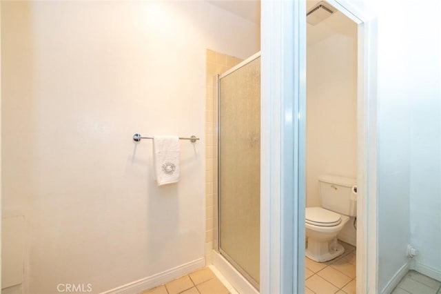 bathroom with tile patterned flooring, a shower with shower door, and toilet