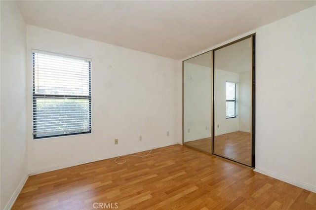 unfurnished bedroom featuring light hardwood / wood-style floors, a closet, and multiple windows