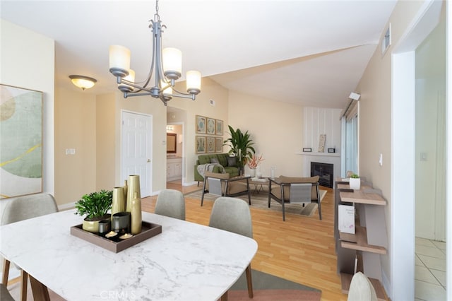 dining room featuring wood-type flooring, a fireplace, and a chandelier