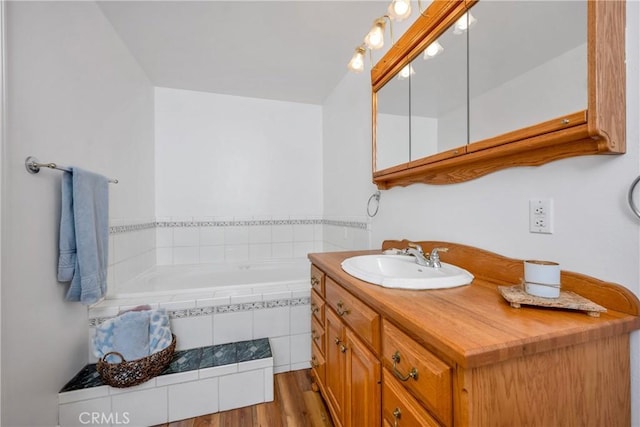 bathroom featuring hardwood / wood-style flooring, vanity, and tiled bath