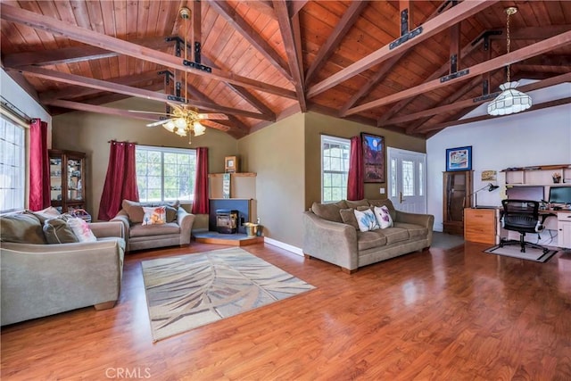 living room featuring beamed ceiling, wood-type flooring, a wood stove, and wood ceiling