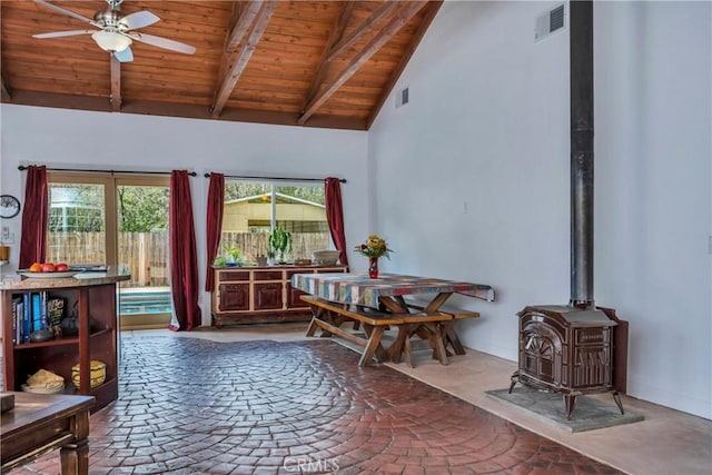 dining space with a wood stove, high vaulted ceiling, ceiling fan, beamed ceiling, and wood ceiling